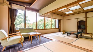 A traditional Japanese room with tatami flooring, a low table, chairs, and a television. - Ooedo Onsen Monogatari Premium Ikaho (Shibukawa)