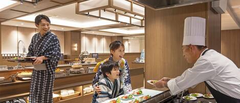 A modern restaurant with a buffet setup, including a variety of dishes and a chef serving food.