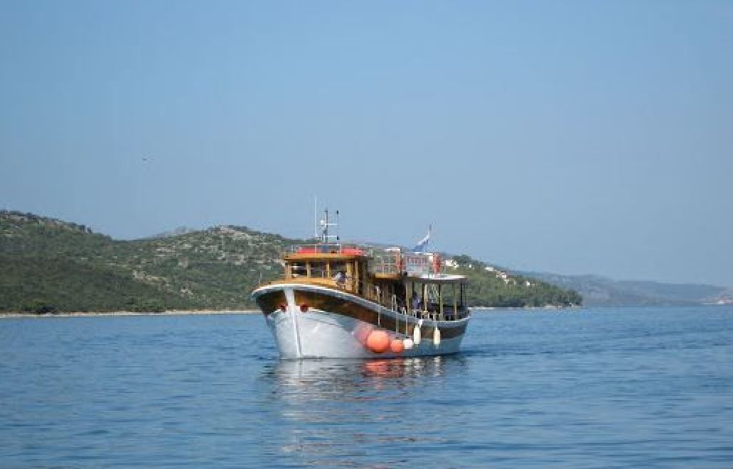 A boat on calm water with a hilly landscape in the background.