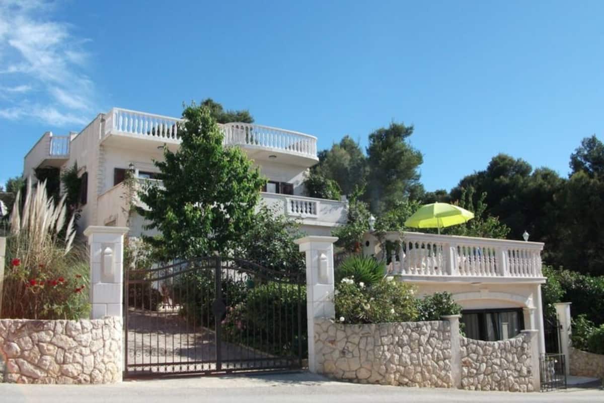 A two-story building with a balcony, stone walls, and a gated entrance.