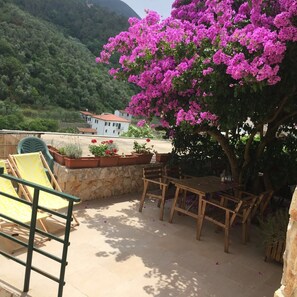 A patio with outdoor furniture, a stone wall, and a view of a house in the background. - Cà di Bianca (Moneglia)