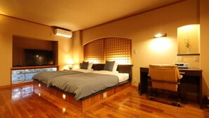 Habitación de hotel con una cama grande, un escritorio con silla, un televisor y una ventana con vistas.