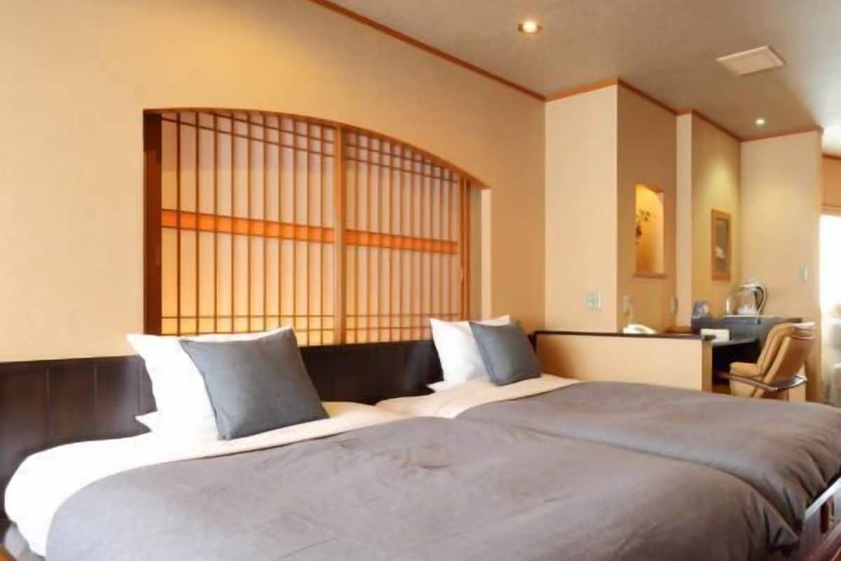 A hotel room with a large bed, a desk, and a mirror.