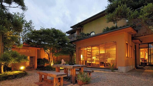 Un edificio tradicional de estilo japonés con terraza de madera y un amplio acceso de vidrio.