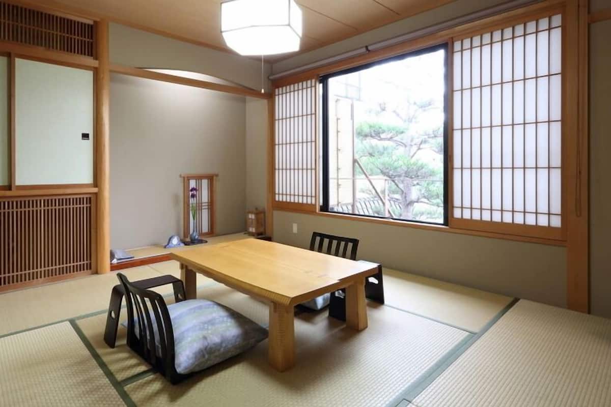 A traditional Japanese room with tatami flooring, a wooden table, and shoji screens.