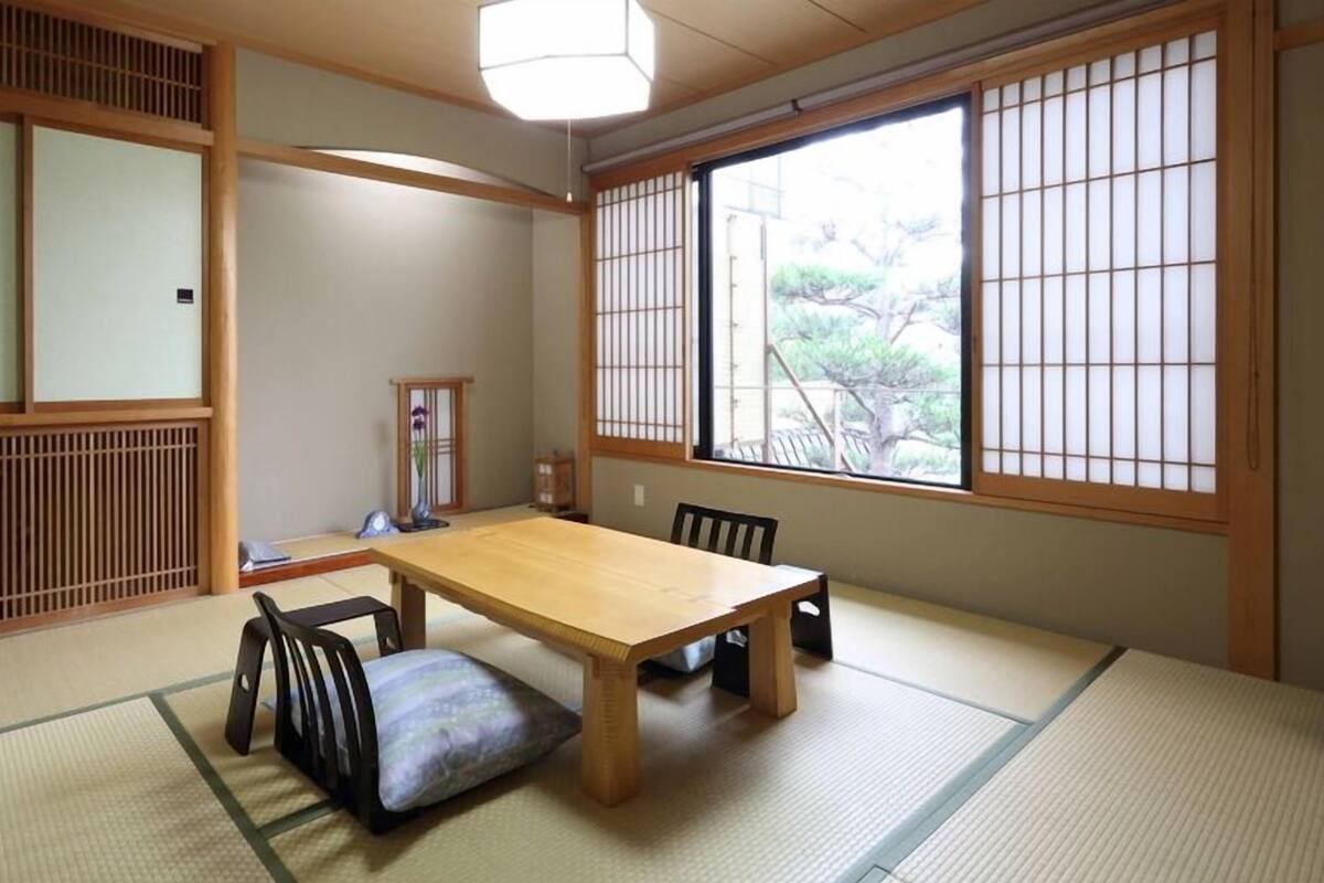 A traditional Japanese room with tatami flooring, a wooden table, and shoji screens.