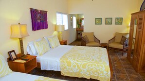 A hotel room with two beds, a sitting area with a chair, a wooden wardrobe, and a view of the hallway. - Coral House (Punta Gorda)
