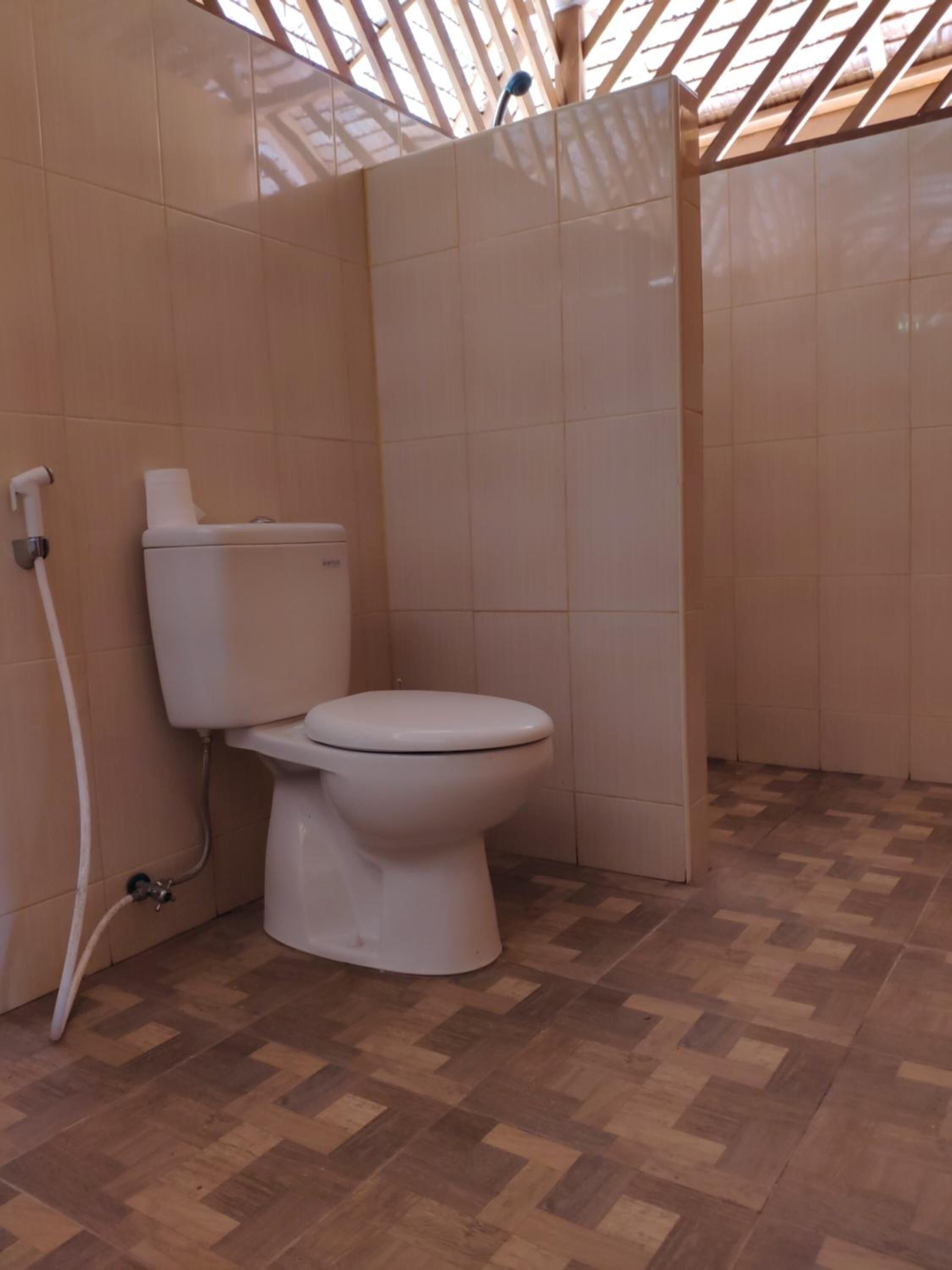 Ein Badezimmer mit Toilette, Duschbereich und Fliesenboden.