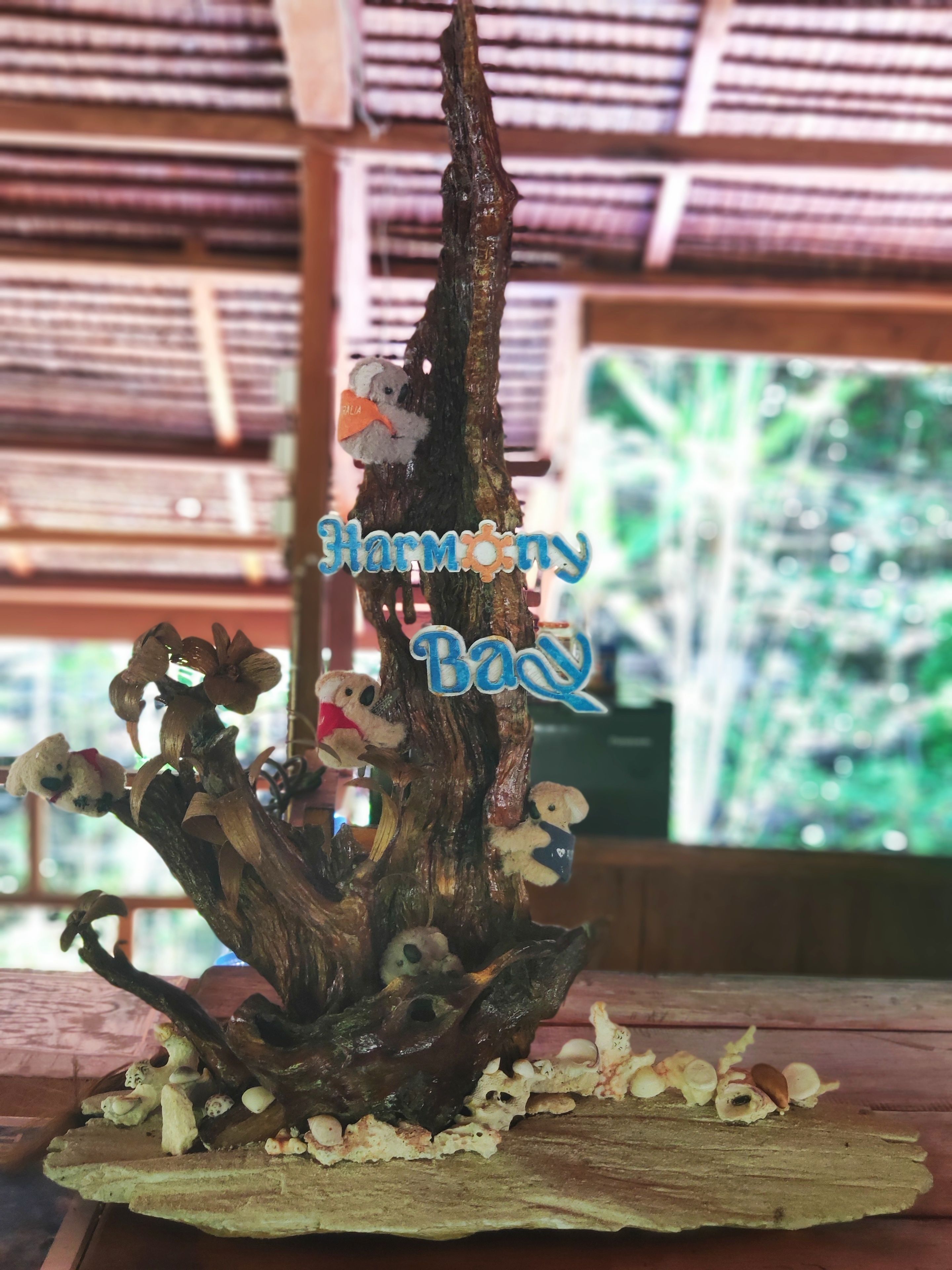 A wooden sculpture with bears and a tree trunk, labeled "Harmony Bay."