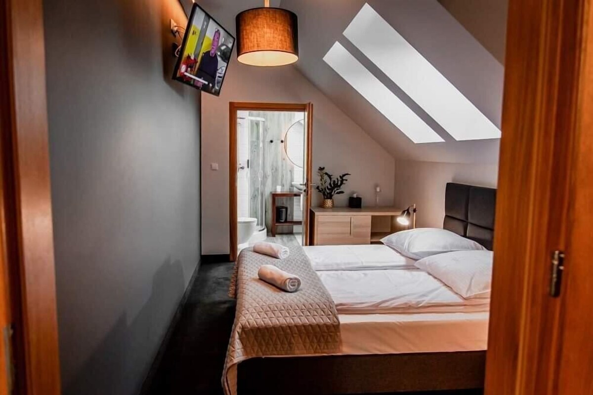 Un dormitorio con una cama, una mesita de noche, una lámpara y una luz de techo.
