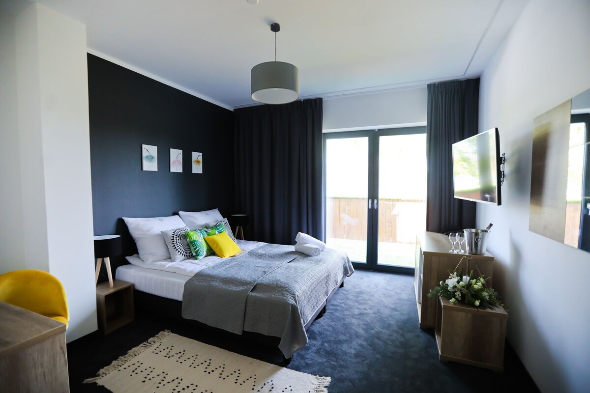 Un dormitorio moderno con una cama grande, una televisión de pantalla plana y un balcón con vistas.
