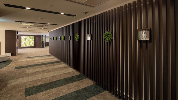 A corridor with a patterned carpet, vertical wooden panels, and small potted plants. - Osaka Airterminal Hotel (Toyonaka)