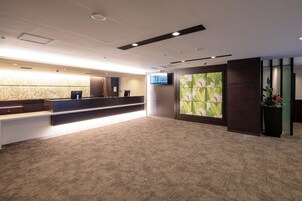A reception area with a reception desk, a digital screen, and a large floral artwork on the wall.