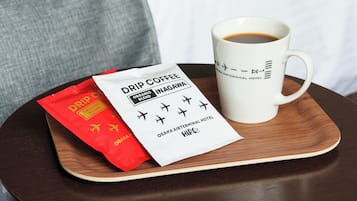 A white mug with a logo, a red packet of drip coffee, and a white label on a wooden tray.