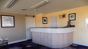 A reception area with a counter, a door, and patterned carpet. - Budget Inn (Tucumcari)