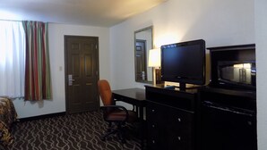 A hotel room with a bed, a desk with a computer and a flat-screen TV, a chair, a dresser, and a door. - Budget Inn (Tucumcari)