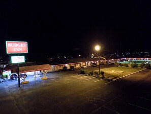 A Budget Inn with a large illuminated sign, a parking lot, and a building with a red roof.