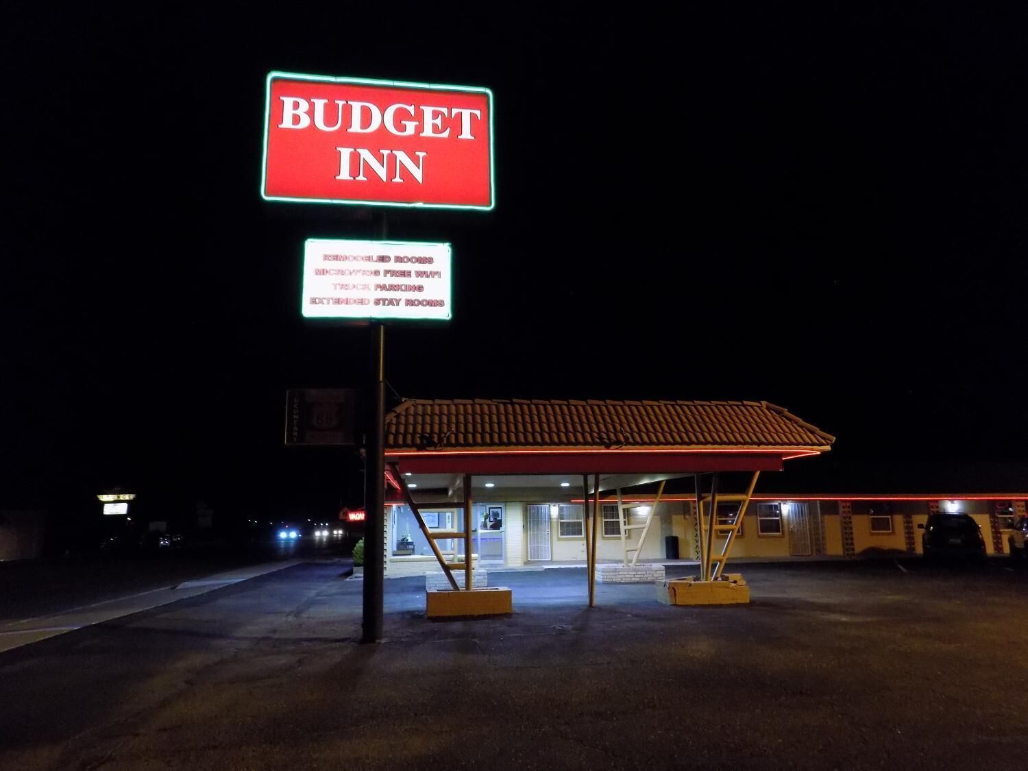 A Budget Inn sign with amenities listed, including remodeled rooms, free WiFi, truck parking, and extended stay rooms.