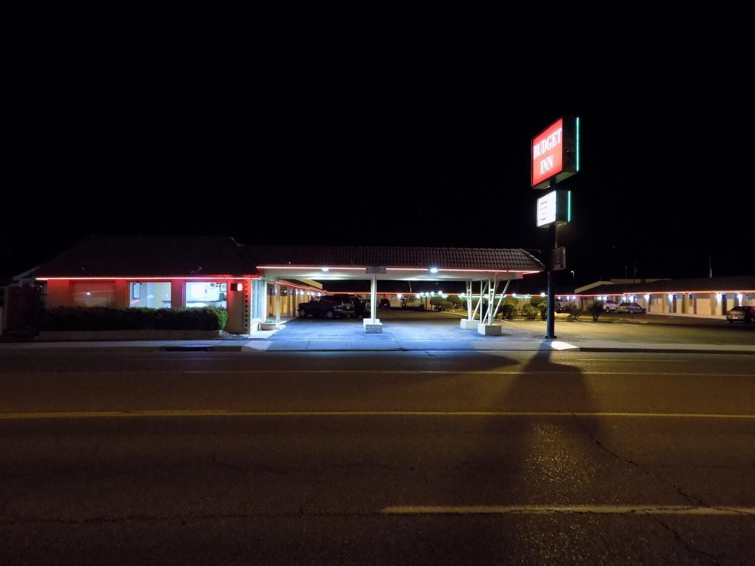 A motel with a covered parking area and a sign indicating it is a Budget Inn.
