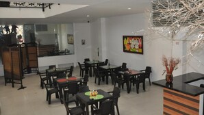 Un espace de restauration moderne, doté de plusieurs tables et chaises, d’un comptoir d’accueil et d’une plante décorative.