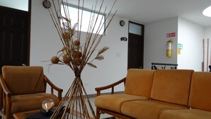 Un salon avec deux canapés marron, une table basse en verre et un arrangement décoratif en bambou.