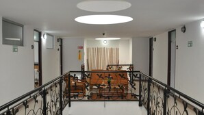 Un hall d’hôtel avec un escalier, un comptoir d’accueil et un espace salon.