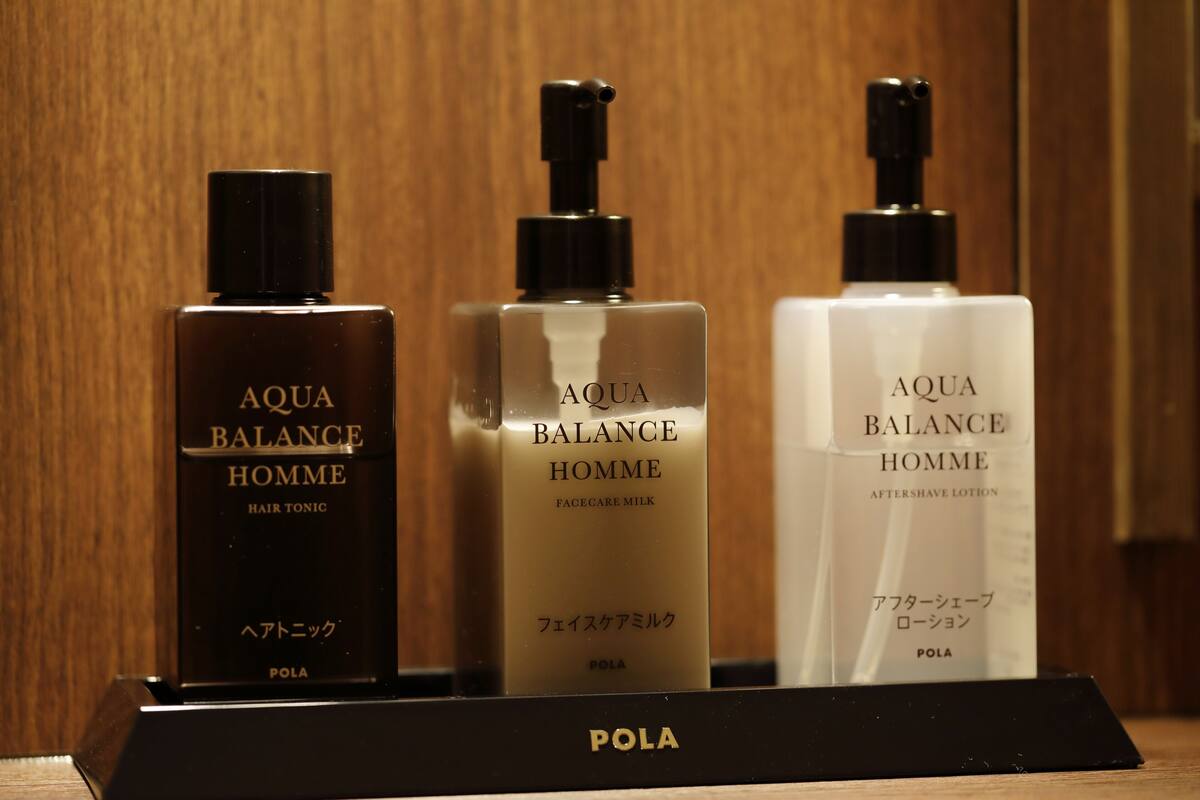Three bottles of AQUA BALANCE Homme on a black display stand.