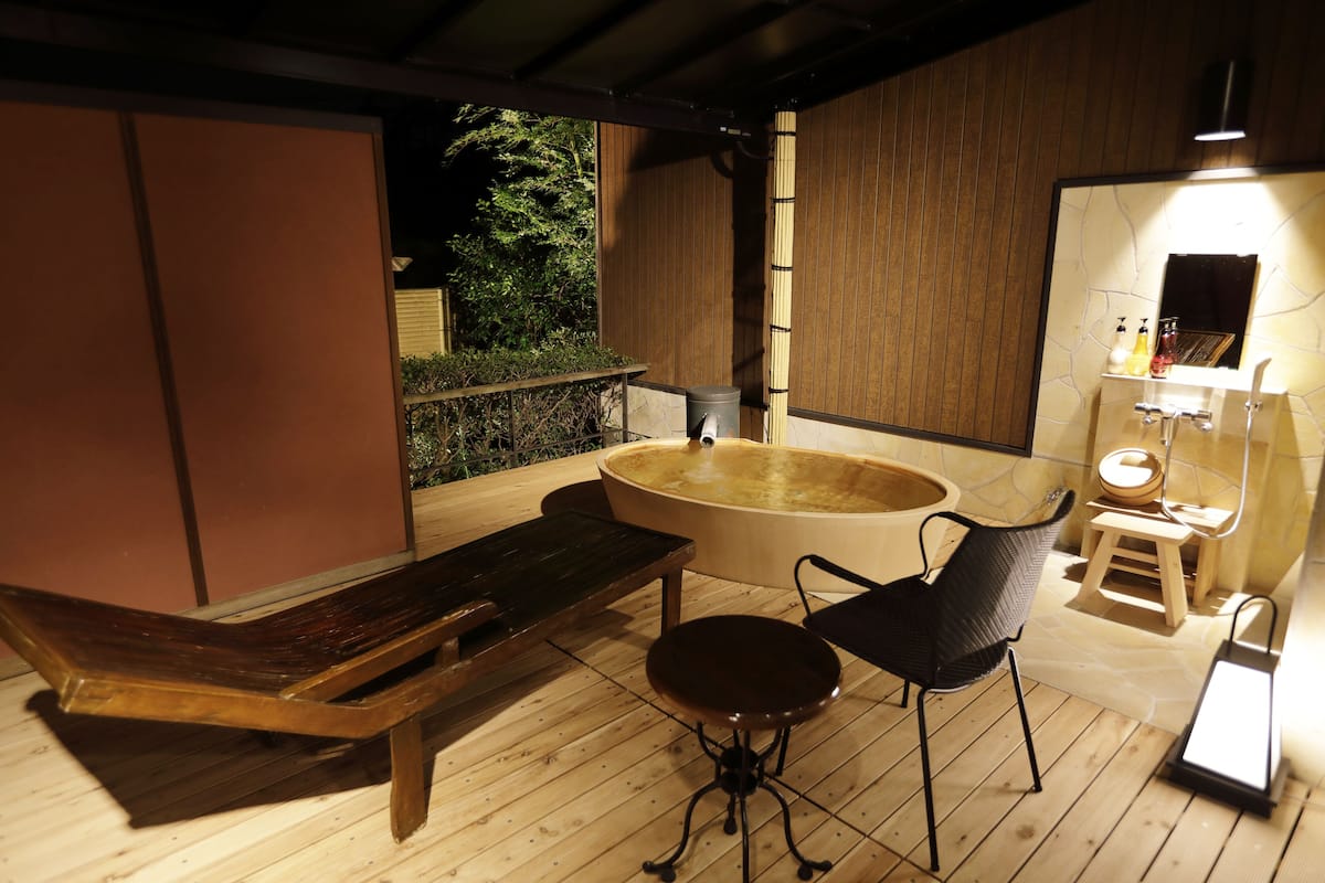 A wooden deck with a hot tub, a bench, and a small table with chairs.