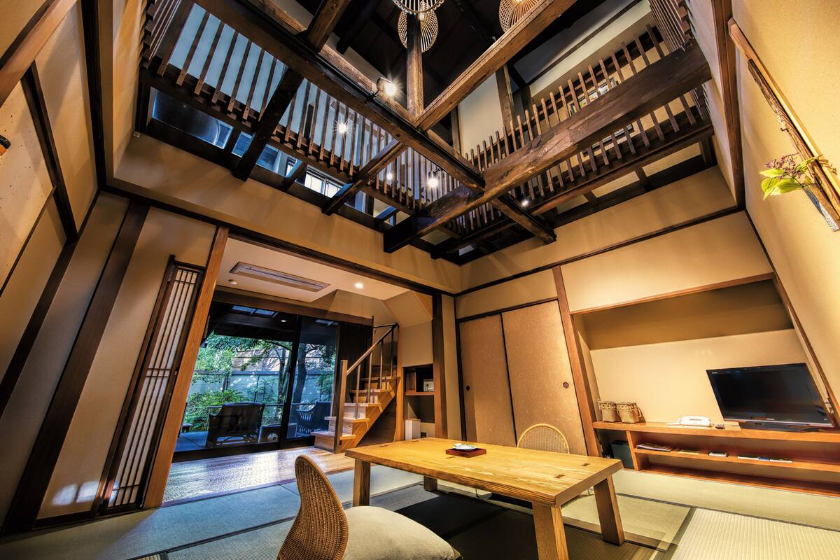 A traditional Japanese-style room with tatami flooring, a low wooden table, and a television on a wooden stand.