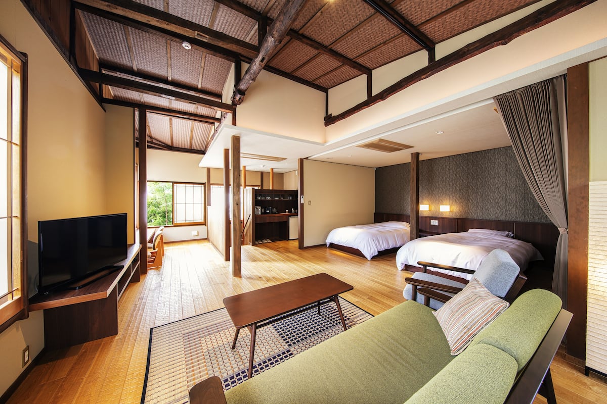 A spacious room with a large bed, a sofa, a TV, and a dining table.