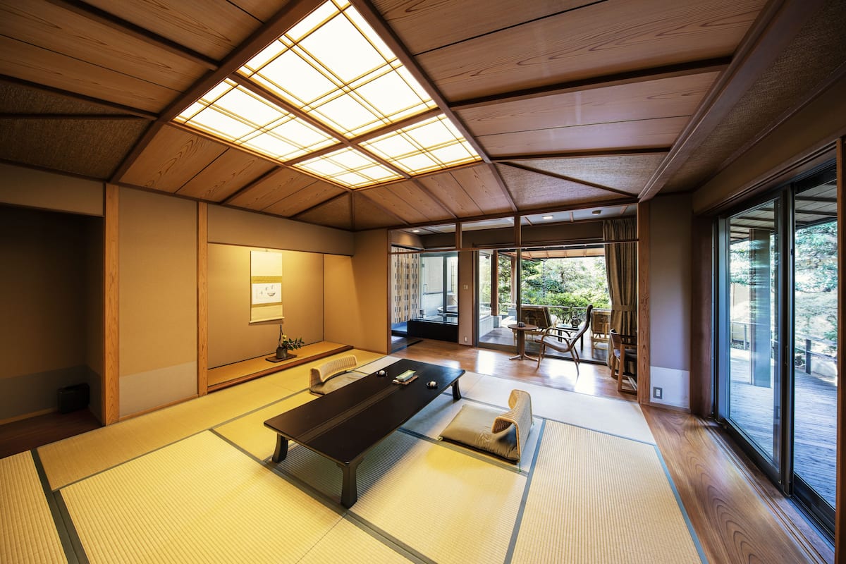 A tatami mat room with a low table, sliding doors, and a view of the outdoors.