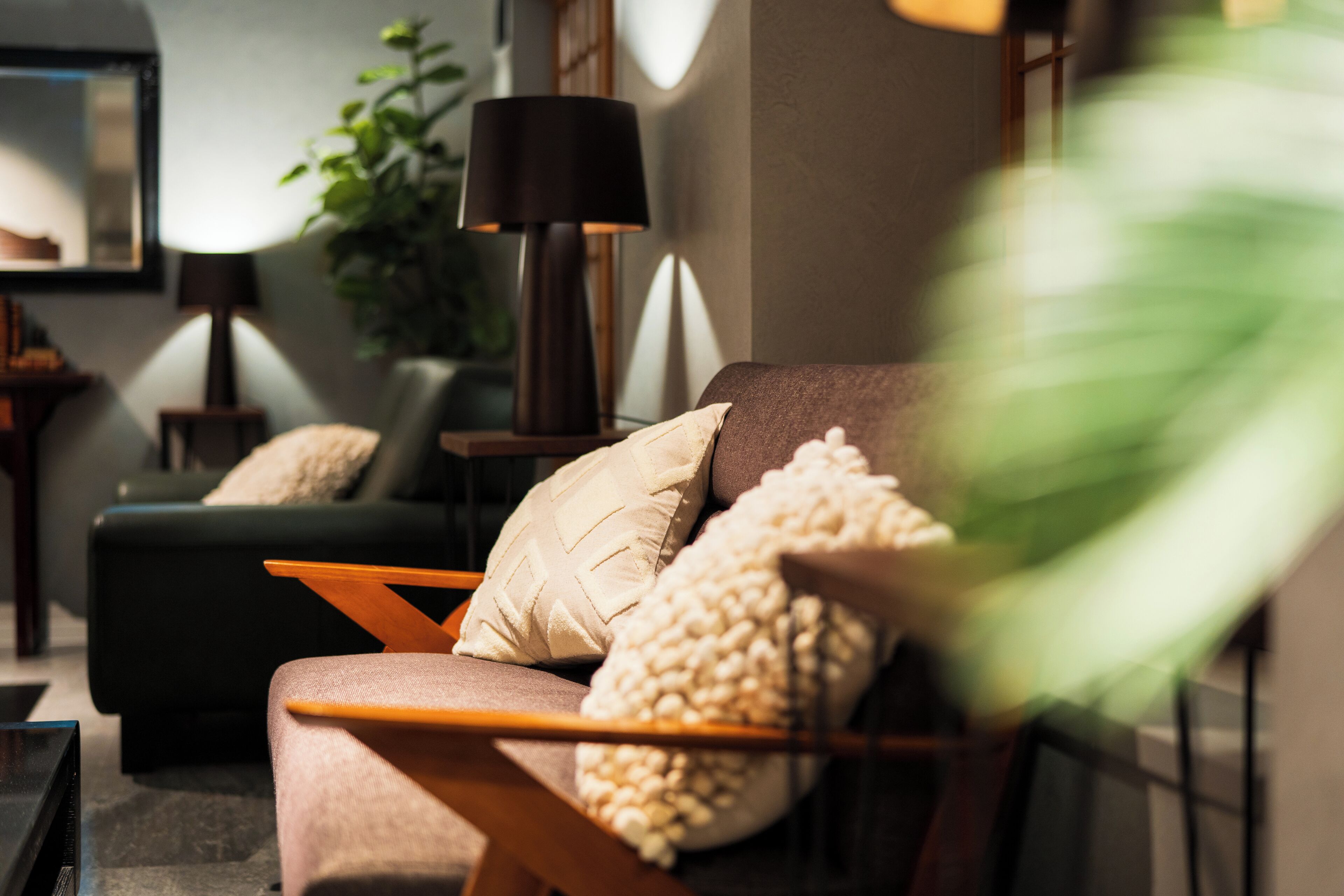 A modern living room with a sofa, a side table, a lamp, and a plant.