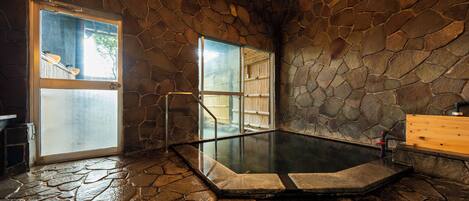 A stone-walled hot tub area with a glass door leading outside.