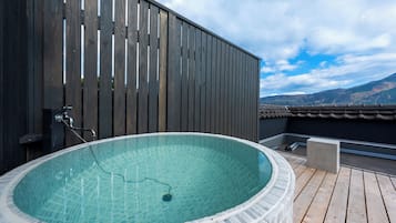 A hot tub on a wooden deck with a view of mountains in the background.