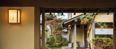 A traditional Japanese garden pathway leading to a building with a wooden structure and a lantern.