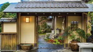A traditional Japanese entrance with a tiled roof, a wooden gate, and a stone pathway leading to a building. - Ryokan Hachisunoito (Yufu)