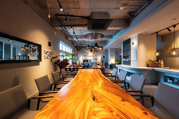 A long wooden table with chairs, a bar area, and a seating area with tables and chairs.