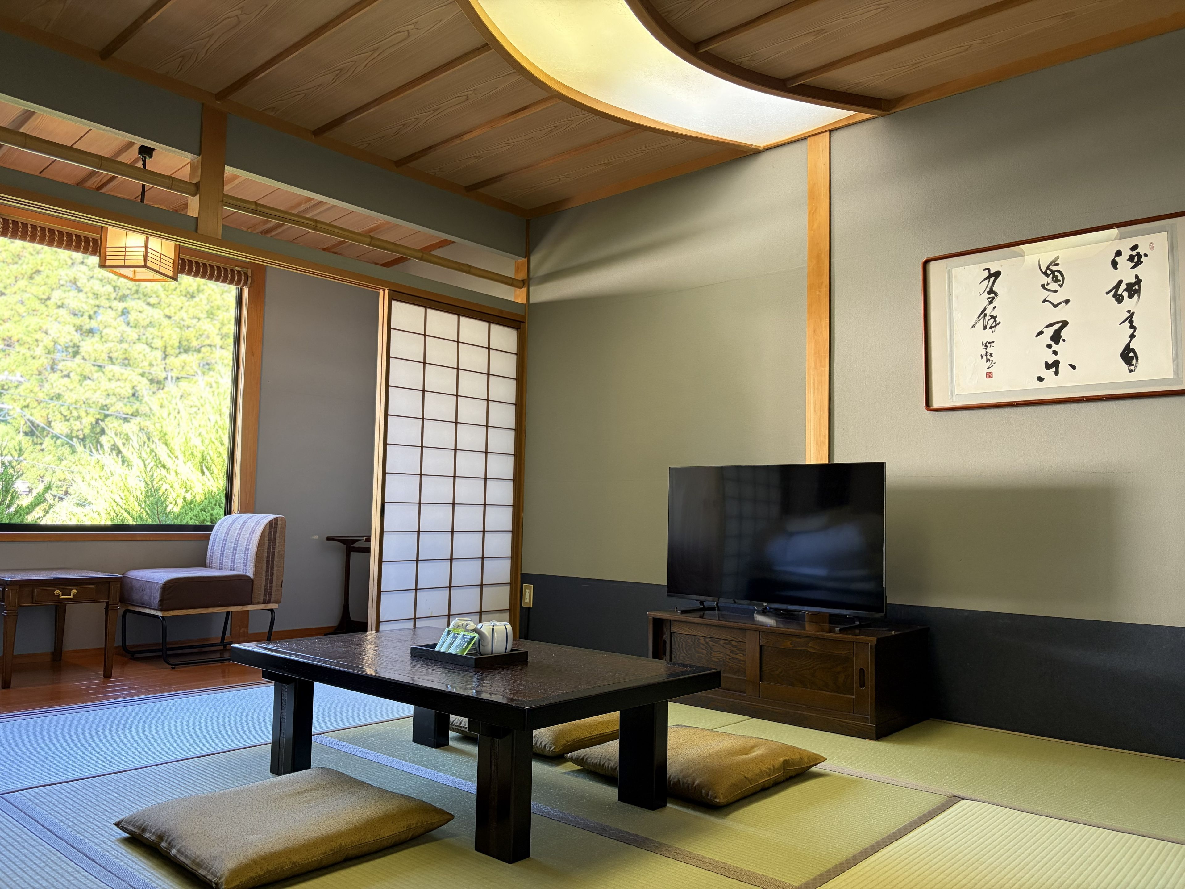 A traditional Japanese room with tatami flooring, a low table, a television, and a sliding door.