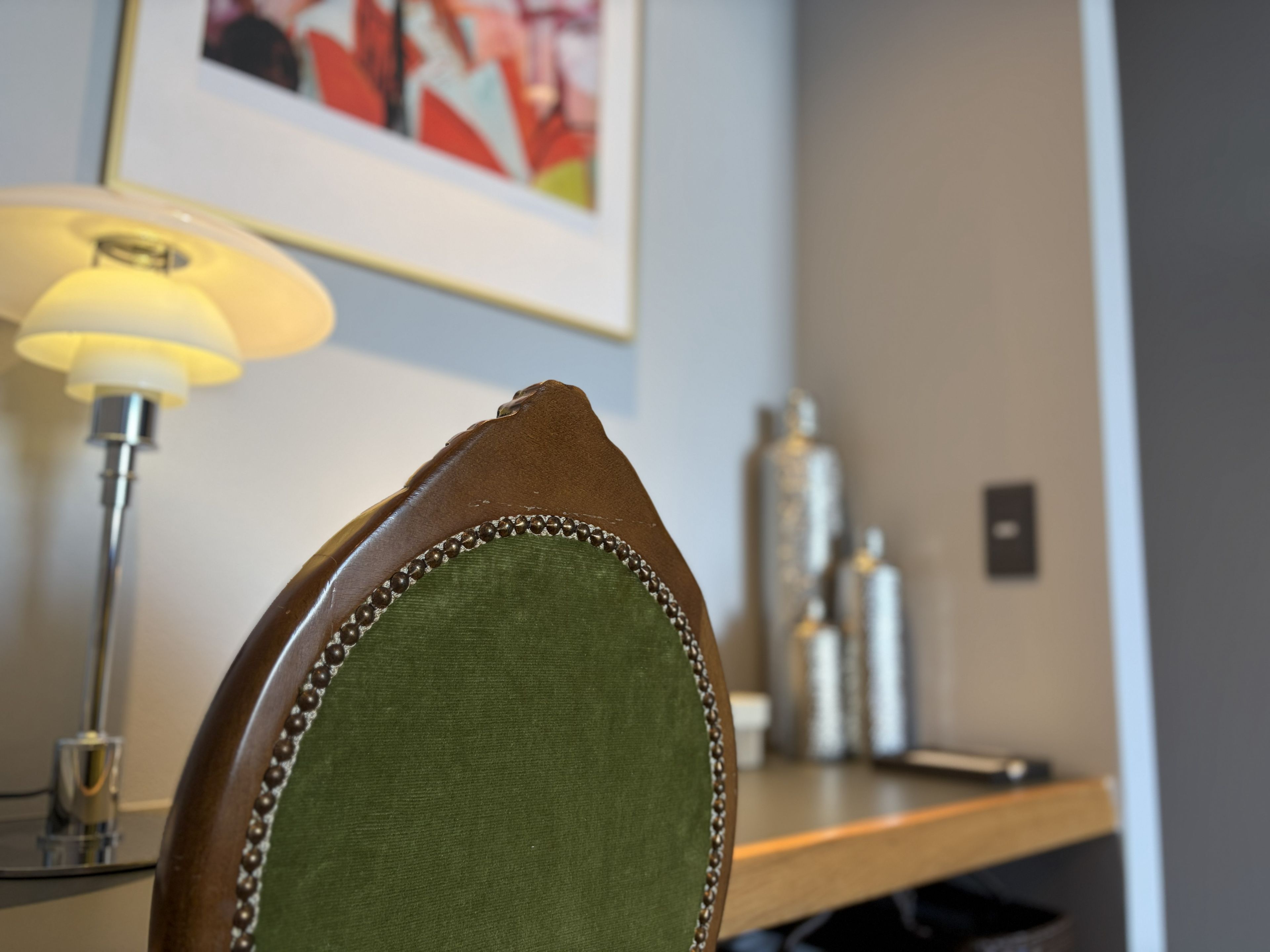 A close-up of a chair with a green fabric backrest and a wooden frame.