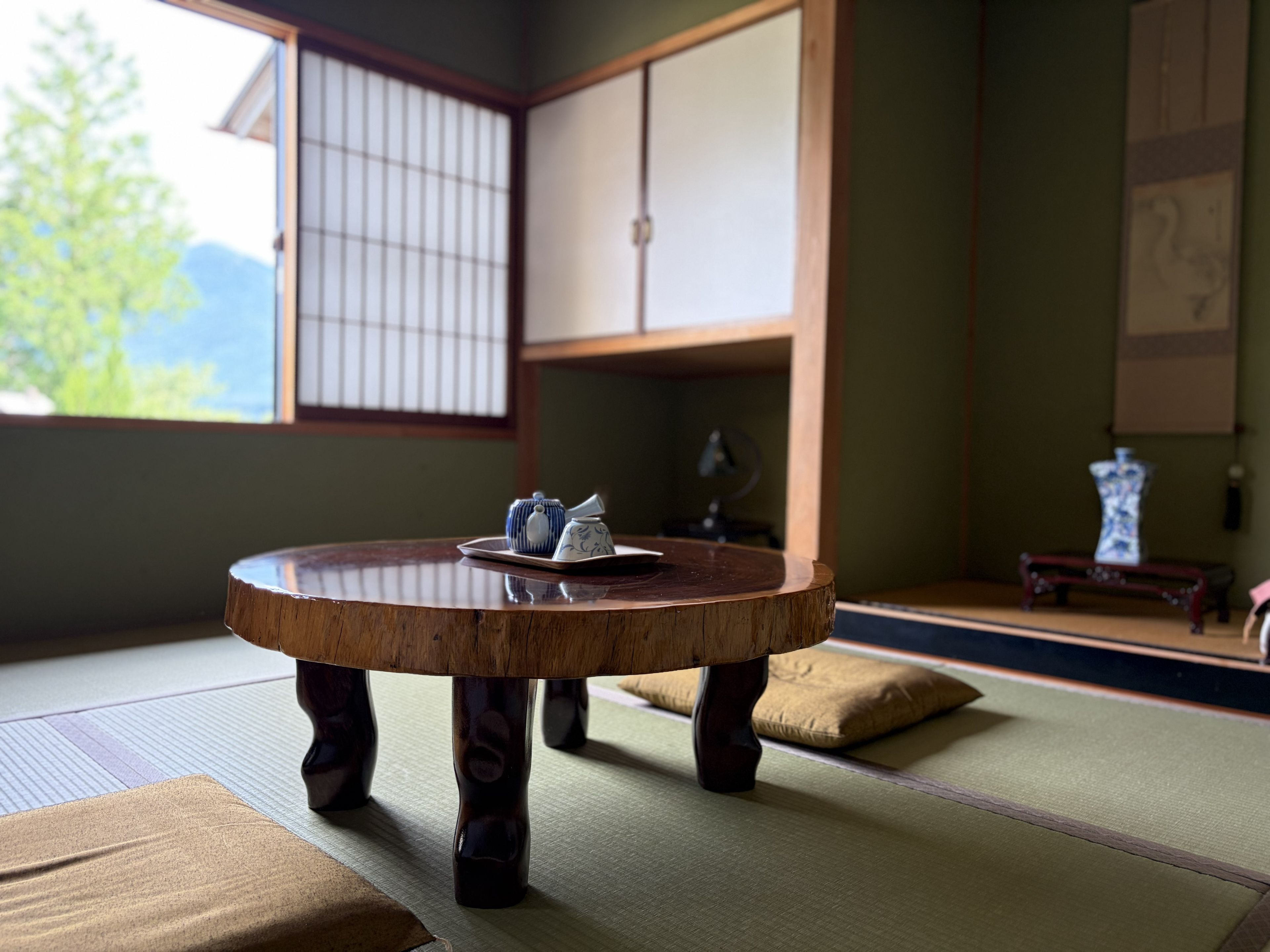 A tatami mat room with a round table, a tea set, and traditional Japanese furniture.