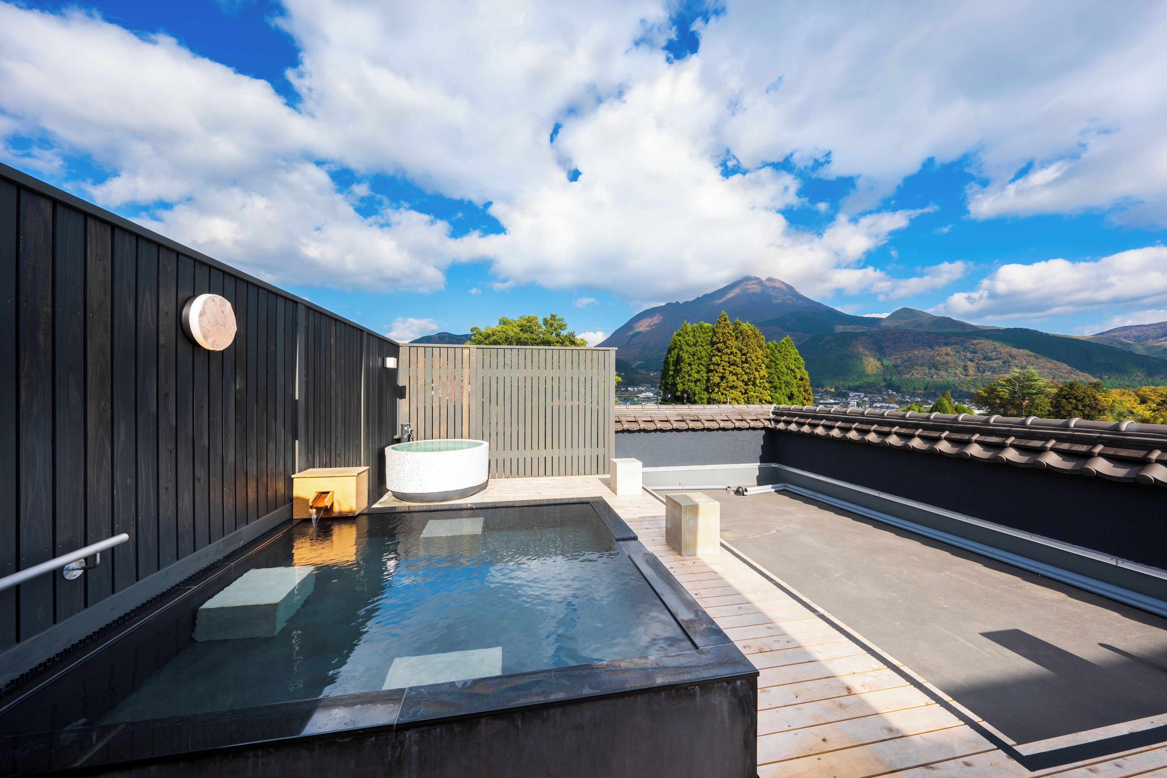 A rooftop hot tub with a view of mountains and a wooden deck.