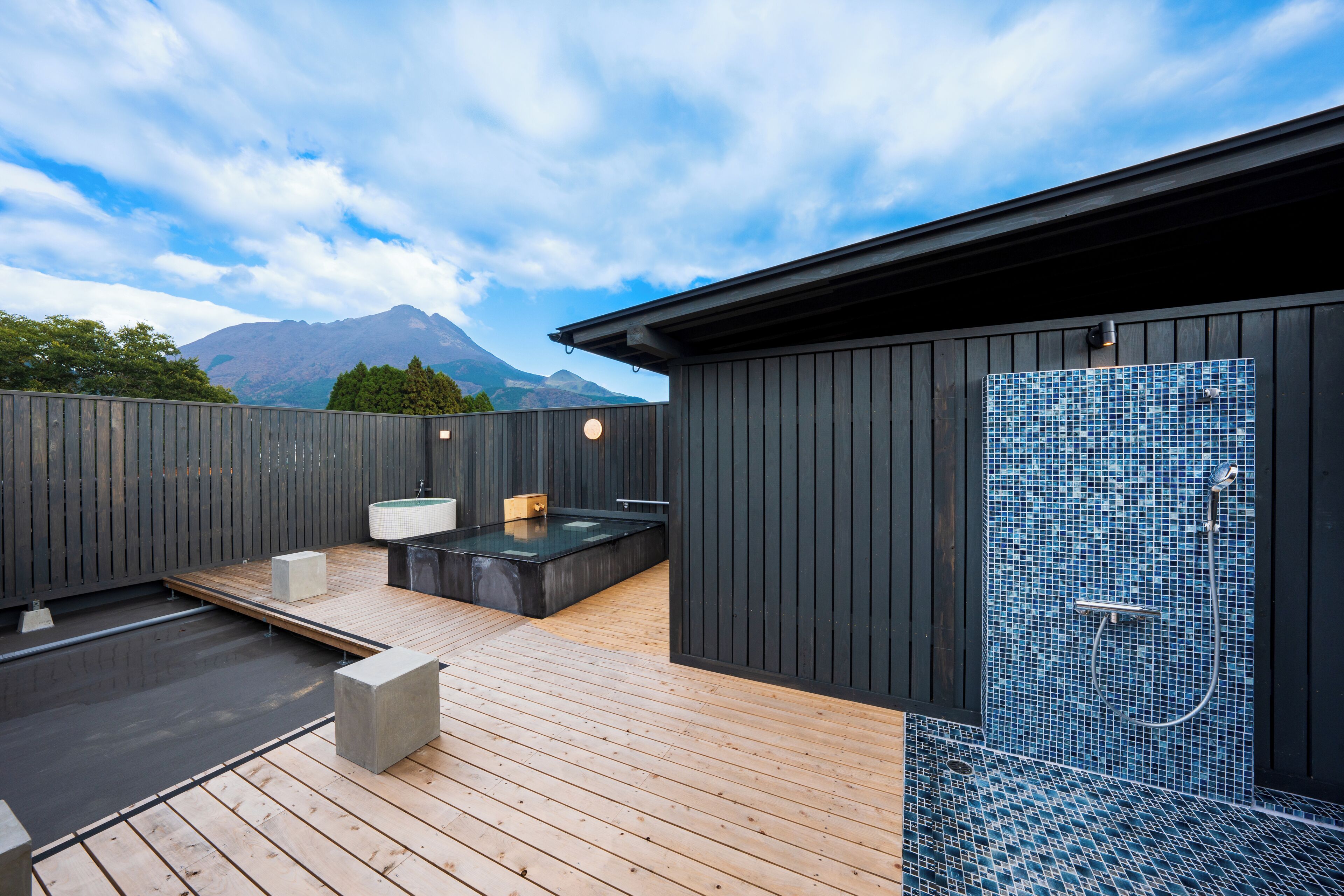 Ett modernt utomhusområde med spa, komplett med ett trädäck, en bubbelpool och en duschavdelning med mosaikplattor.