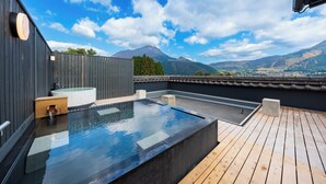 A rooftop pool with a hot tub, wooden deck, and a scenic mountain view. - Ryokan Hachisunoito (Yufu)