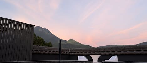 A rooftop pool with a view of mountains and a traditional tiled roof.