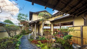 A traditional Japanese garden with a stone pathway, wooden structures, and various plants. - Ryokan Hachisunoito (Yufu)