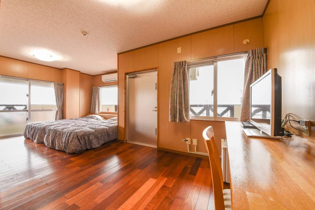 Una habitación con cama, escritorio, silla, ventana y puerta.