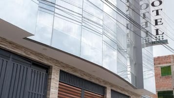 A modern hotel with a reflective glass facade, a prominent sign, and a gated entrance.