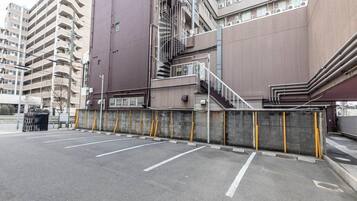 A parking area with a concrete barrier and a staircase leading to a building.