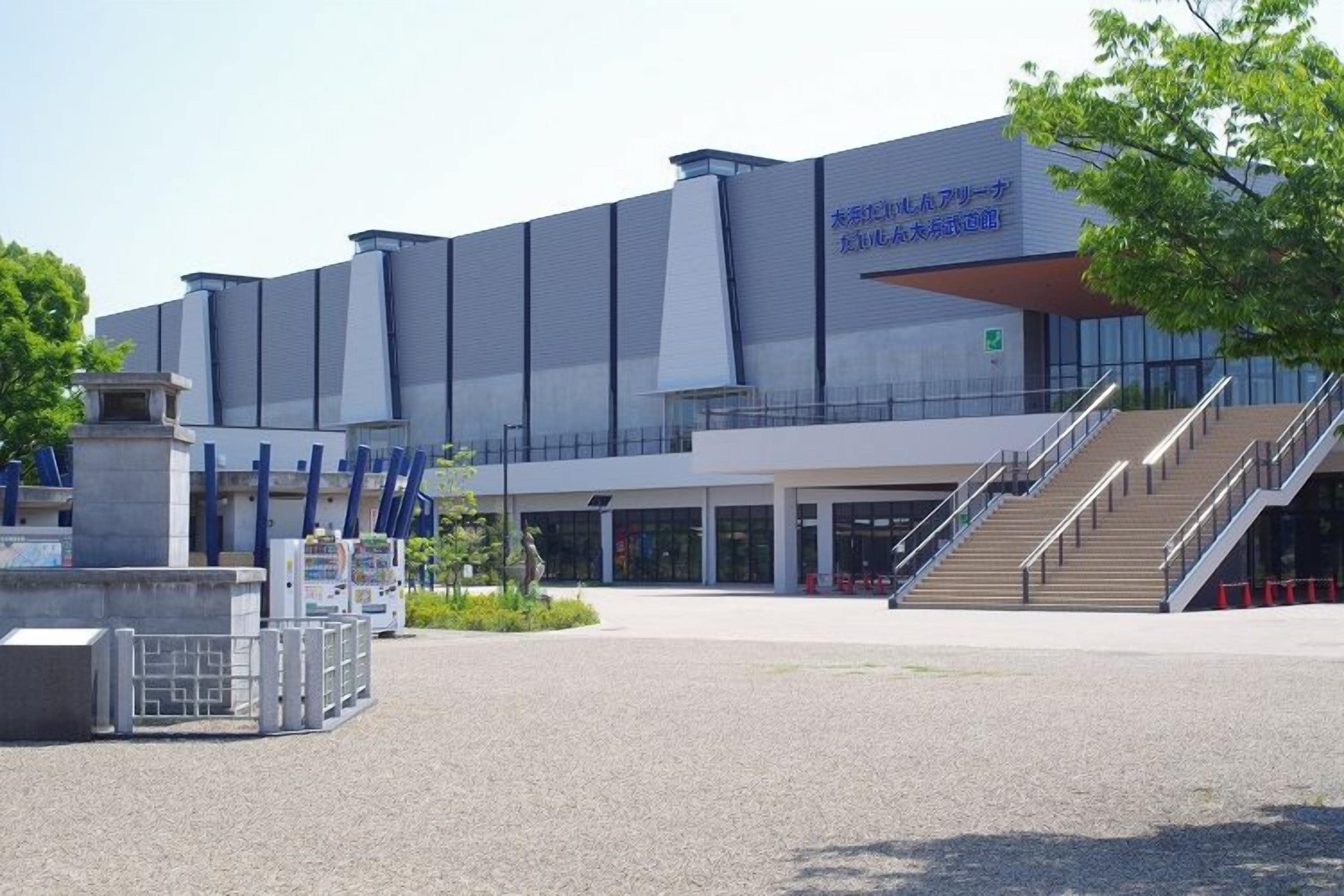 Een modern gebouw met een ruime ingang, een trap en een bord met tekst in een vreemde taal.