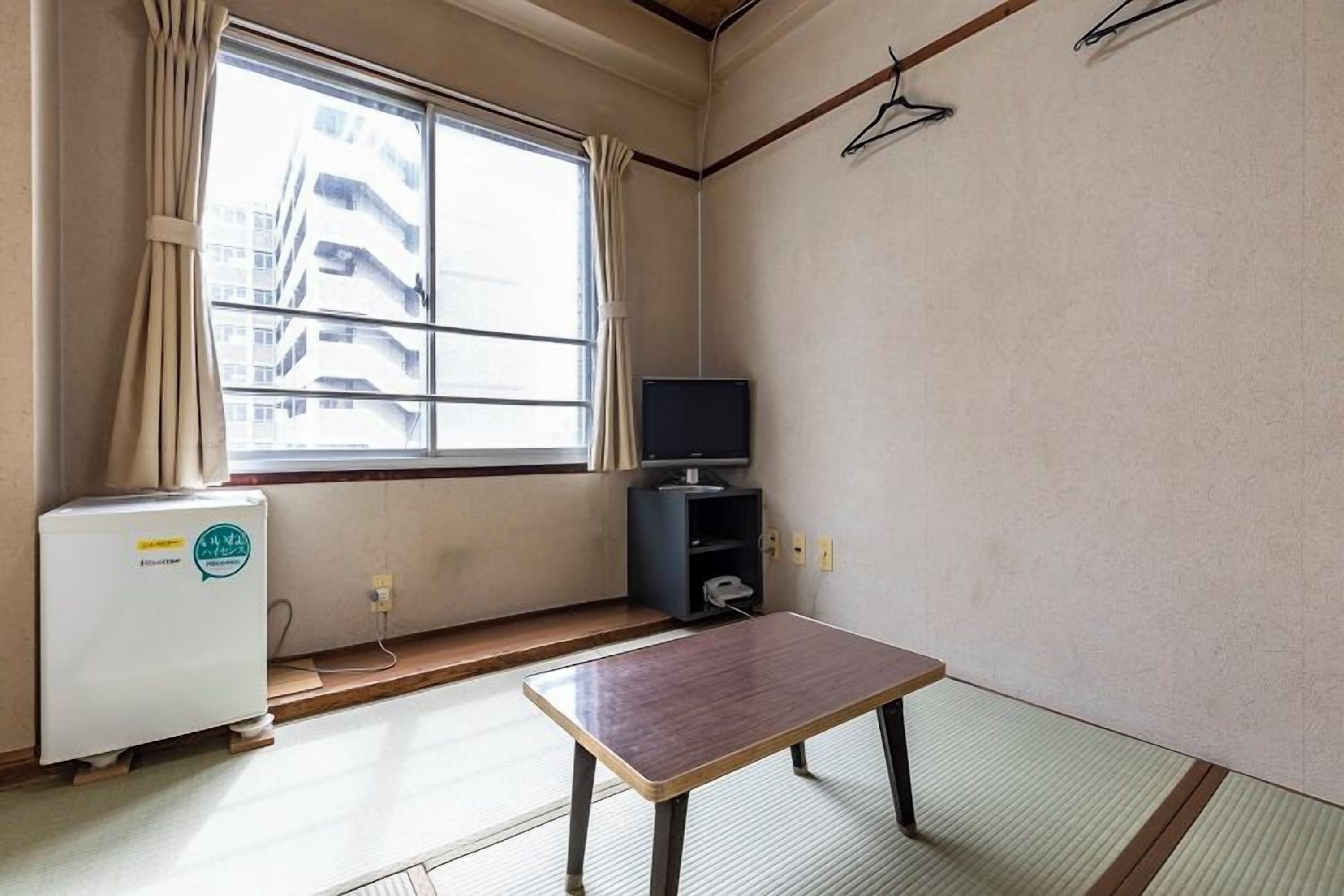 Una habitación con suelo de tatami, una mesa baja, un televisor y un calentador.